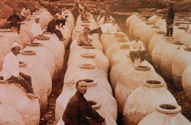 Fotografía histórica de alfareros georgianos sentados sobre decenas de qvevris de barro recién fabricados